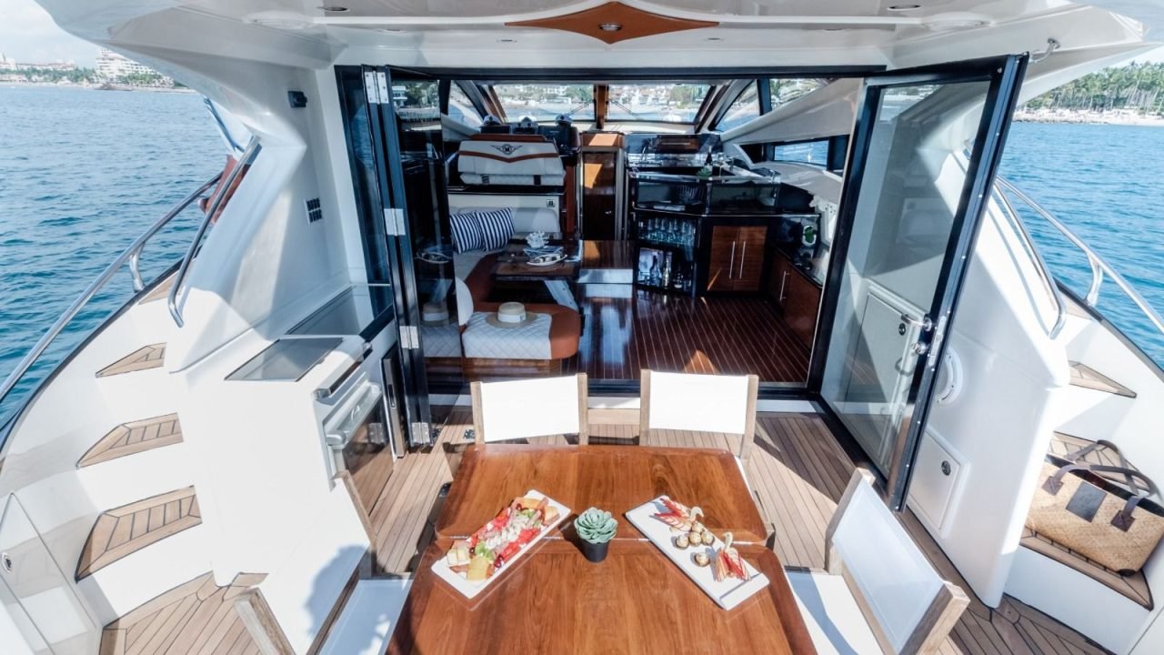 Mesa de teca con botanas en la popa del yate Marquis 50 SC, abierta al salón interior: yate privado en Puerto Vallarta para aniversarios